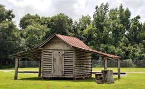 Small wood and log structure with tin roof - probably a farm shed or chicken coop originally