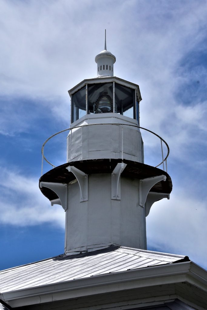 Closeup of the top of the Seahorse Key Lighthouse against the blue sky.