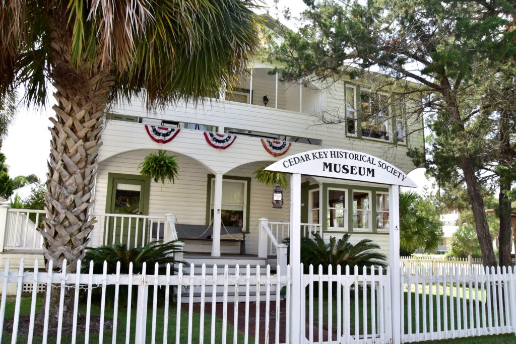 Photo of the Cedar Key Historical Society Moseum, a beautiful old 2-story clapboard house surrounded by a white picket fence.