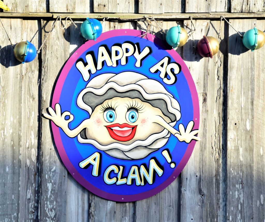 Colorful sign of cartoonish clam with a big smile "Happy as a Clam"