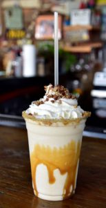 Large drink with caramel dripping down the sides, topped with shipped cream and pecans