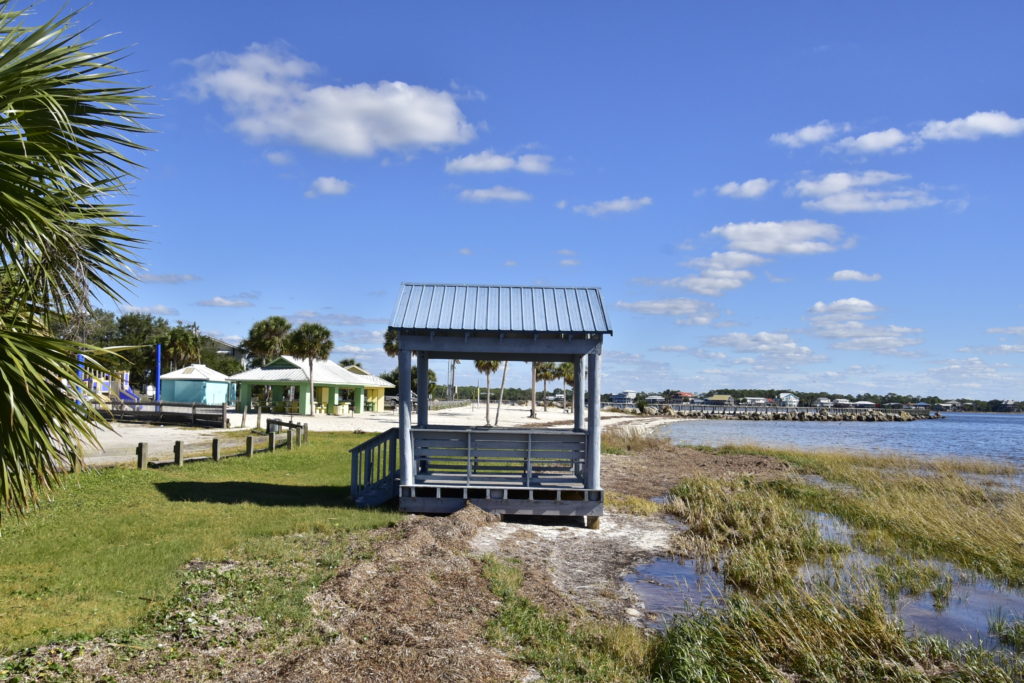 A gazebo on the sandy corner of a beach, playground in the background