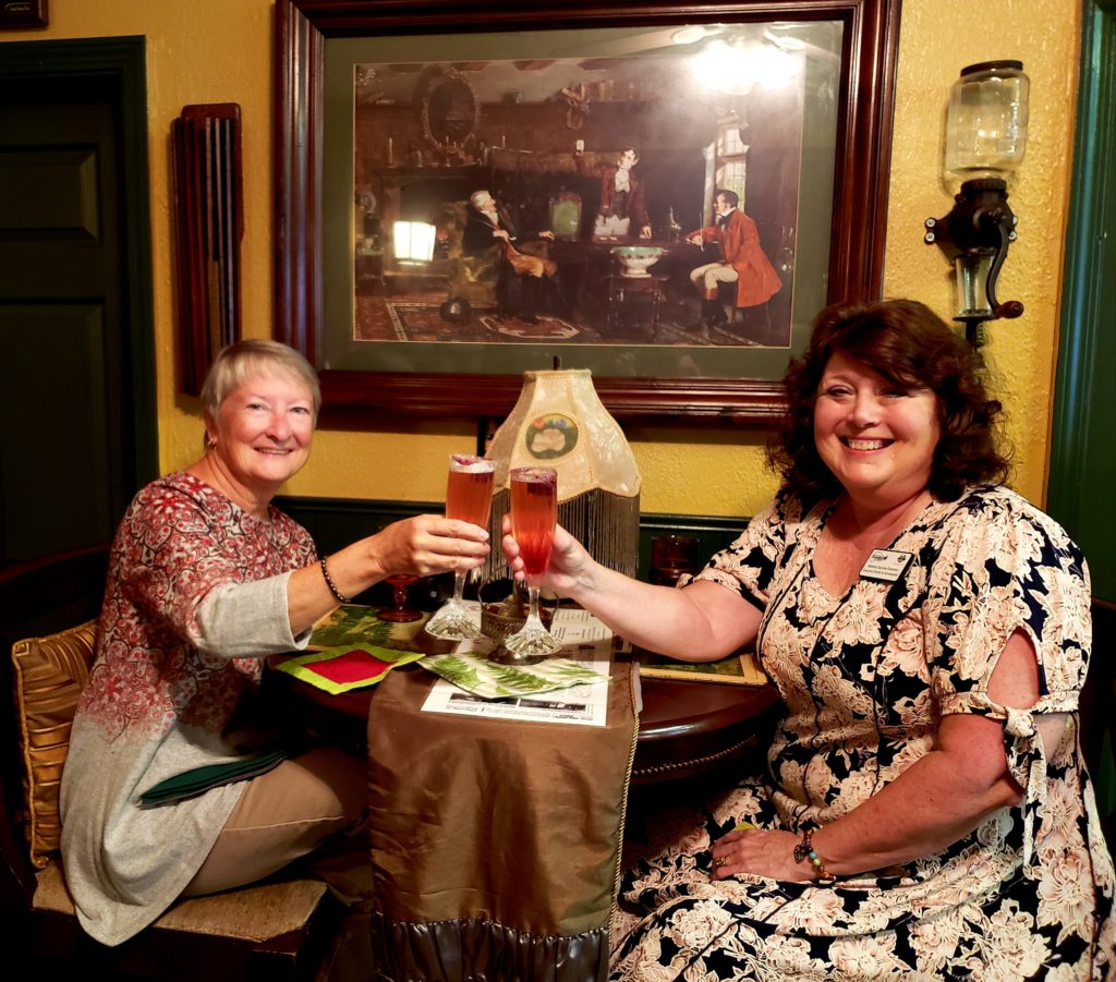 Two ladies at table with bubbly drinks, toasting