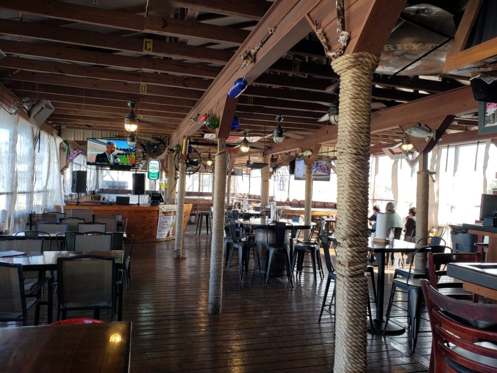 a nearly empty restaurant with tv on, and columns wrapped in hemp roap