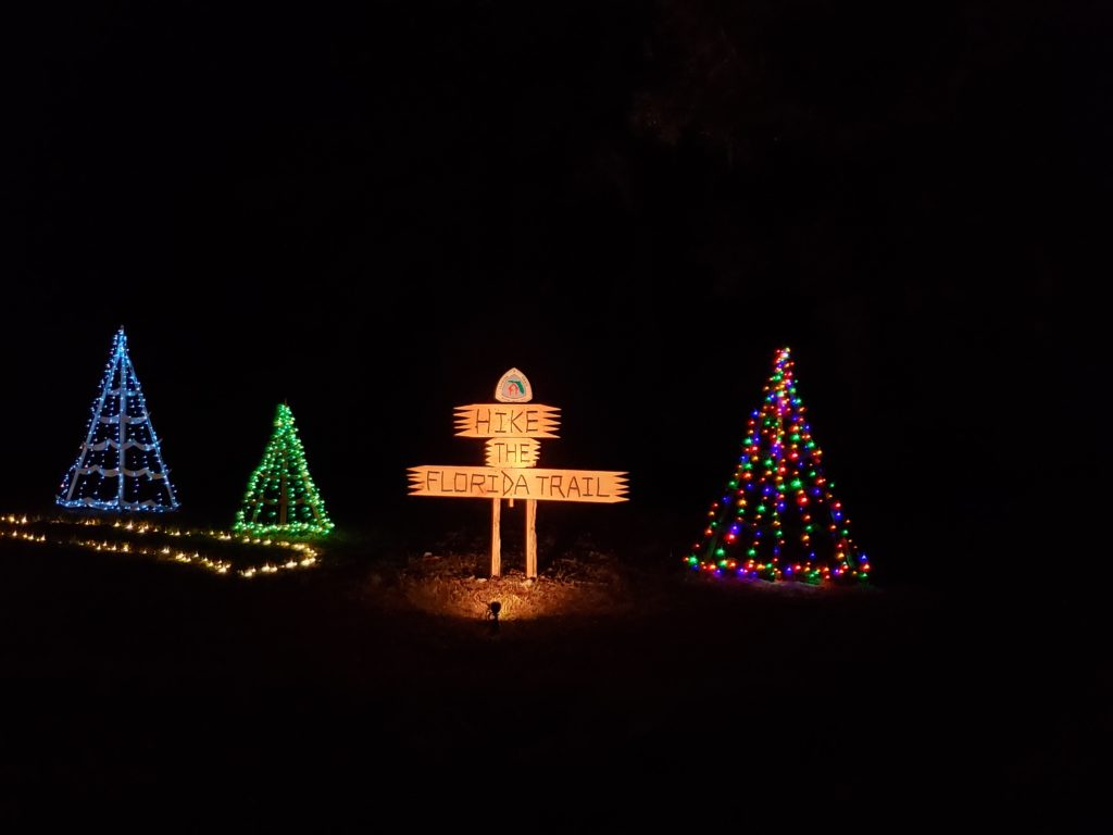 Festival of Lights display of Christmas trees and trail-sign-style sign for The Florida Trail organization