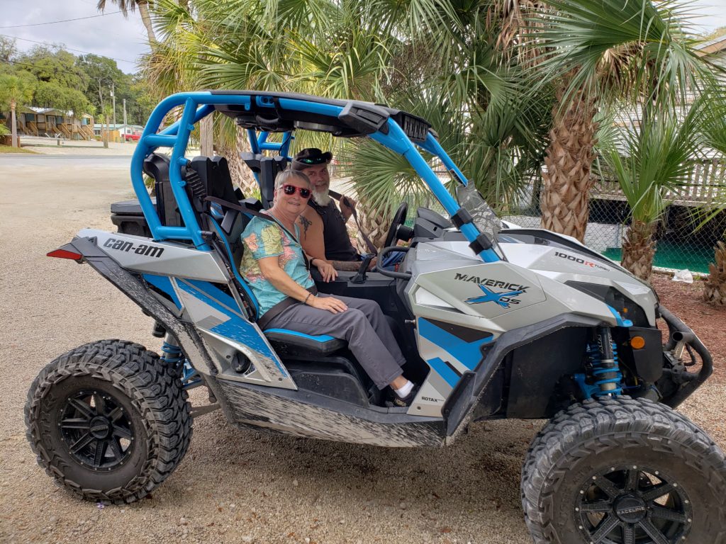 man and woman in a side-by-side ATV starting off on a day of adventures