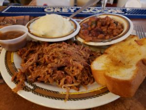 plate filled with pulled pork BBQ, mashed potatoes, BBQ beans and texas toast