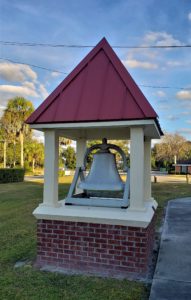 Bell mounted in steeple on ground