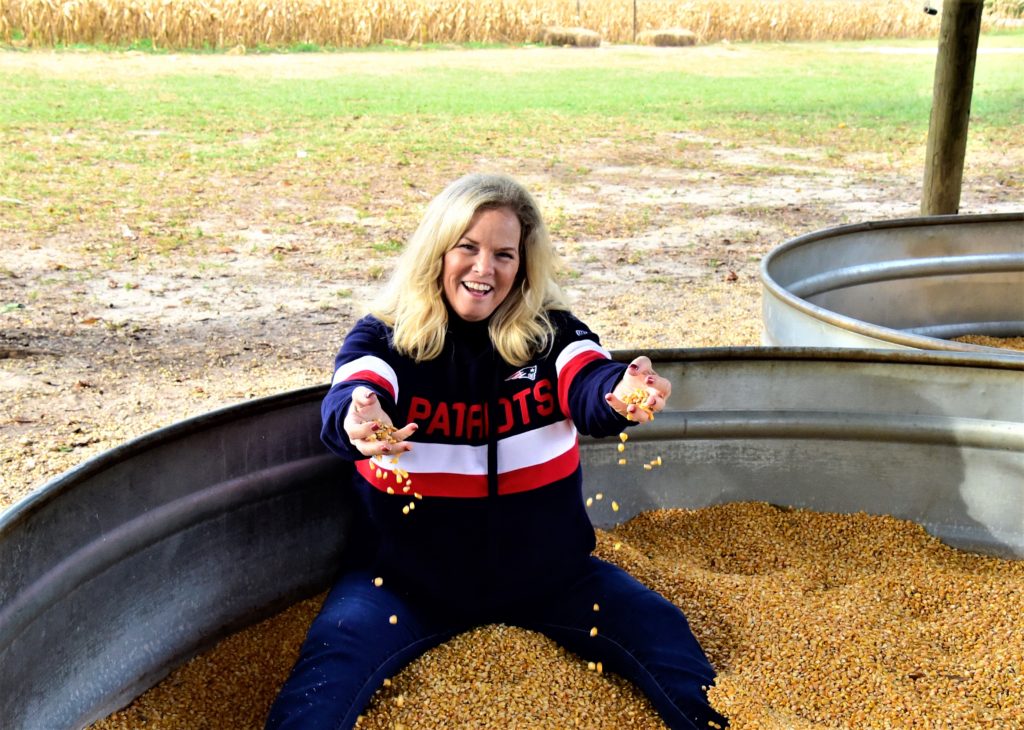 Woman sitting in a feed tub filled with corn kernals 